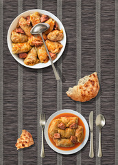 Pickled Cabbage rolls with leavened flatbread torn loaf served on rustic dark brown paper parchment place mat