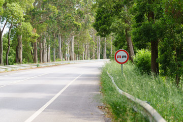 Asphalt road through the forest in Northern Portugal. "Prohibition of overtaking" sign