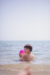 Fototapeta na wymiar Adorable boy standing in the water on the beach