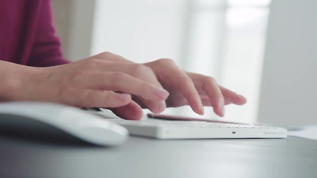 Close-up: women's hands quickly typing on the keyboard of the computer. Text or message typing. Woman is working in the office and typing text, clicking on the buttons. Concept text, work, office work
