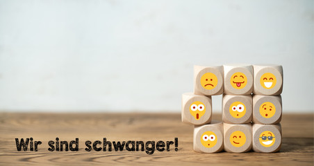 Viele Würfel mit Emoticons und die Ankündigung "Wir sind schwanger!"