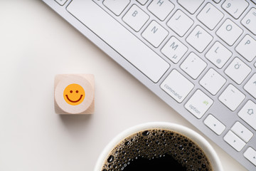 Würfel mit lächelndem Smiley am Arbeitsplatz