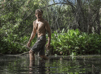 Fototapeta na wymiar Sexy adventure man wading through swamp