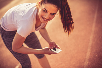Typing messages at break from exercise. Young woman.