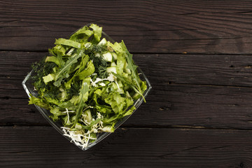 Vegetable salad with fresh vegetables on a wooden table. Salad with green fresh vegetables in a glass bowl. Vegetarian food salad. The concept of a healthy diet

