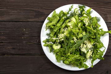 Vegetable salad with fresh vegetables on a wooden table. Salad with green fresh vegetables in a glass bowl. Vegetarian food salad. The concept of a healthy diet
