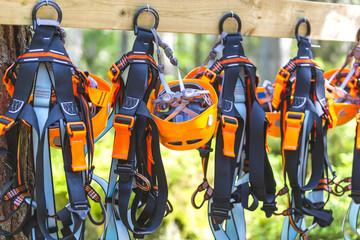 Climbing gear equipment - orange helmet harness zip line safety equipment hanging on a board. Tourist summer time adventure park family and company team building concept for extreme recreation sports