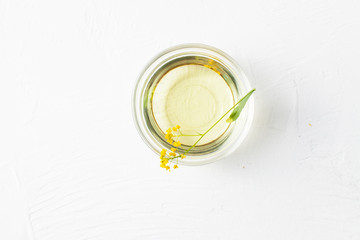 Sprigs of winter cress with a bowl of vegetable oil on a white background.