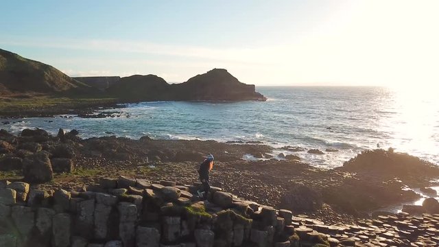 4k Aerial Shot of female enjoying the view on Giant's Causeway rocks in Northern Ireland