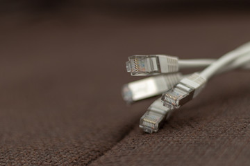 Bunch of network cables lying on a brown fabric furface
