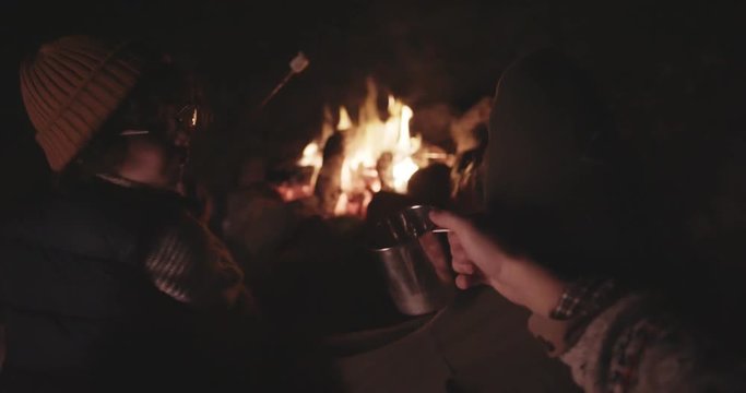 Father and son campers relaxing by bonfire and roasting marshmallows