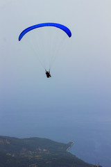 A man in a parachute is flying over the mountains. Parasailing.