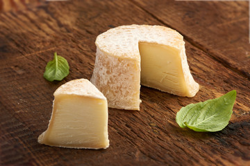 Crottin cheese with basil leaves on rustik wooden background