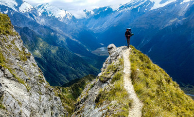 traveler at the edge of a cliff with amazing view behind him.Cascade Saddle, Mount Aspiring...
