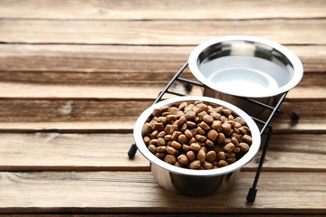 Cat food and water in bowls on wooden table