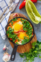 Shakshuka. Frying pan with eggs in tomato sauce.