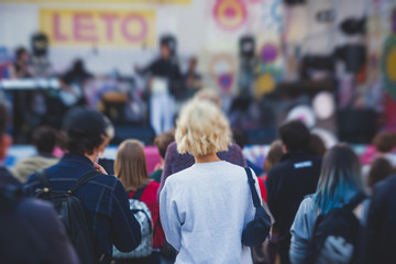 A crowded concert hall with scene stage lights, rock show performance, with people silhouette and hand holding smartphone