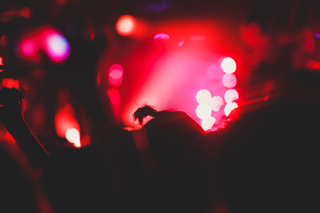 A crowded concert hall with scene stage lights, rock show performance, with people silhouette and...