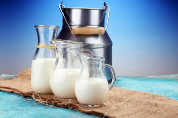 A jug of milk and glass of milk on a wooden table