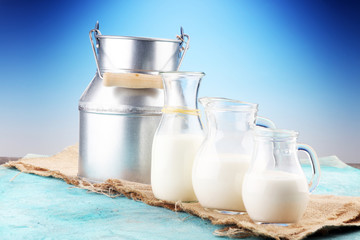 A jug of milk and glass of milk on a wooden table