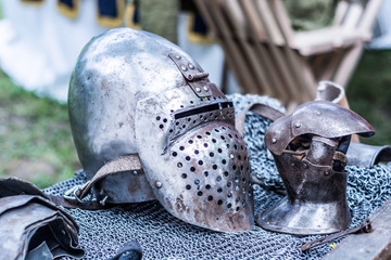Iron helmet and protective metal glove of the medieval knight on desk with chain mail. Middle ages...