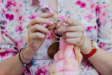Hands of a young woman knitting clothes. The concept of women's leisure and needlework.