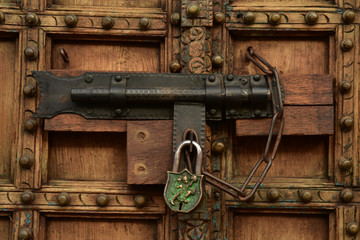 vintage wood door with brass fixtures bolt lock and padlock