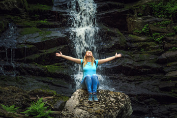 Girl traveler near a forest waterfall.