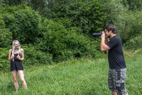 Fotograf mit Digitalkamera fotografiert blonde junge Frau in der Natur