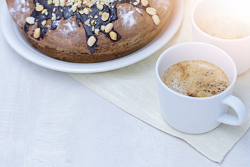 Homemade cake with nuts and chocolate and two cups with coffee on wooden white table