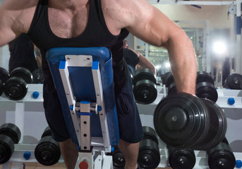 Fototapeta na wymiar Bodybuilder with dumbbells, trainings in a gym