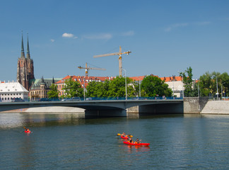 River and bridge view in Wroclaw, Poland. Old architecture church,  cranes and kayaks.