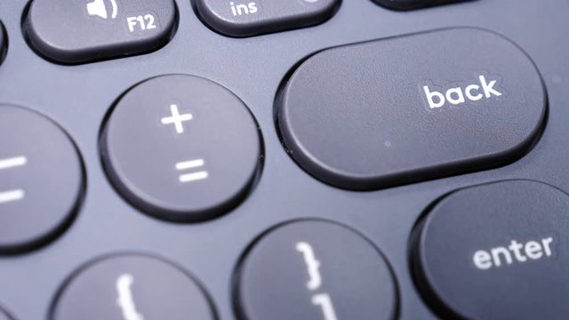 Closeup of finger pressing backspace button on the black computer keyboard. Technology. Slow motion