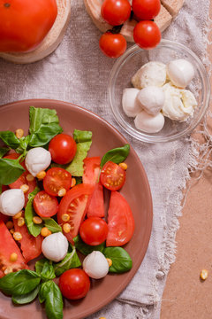 Traditional Italian fresh salad Caprese made of organic cherry tomatoes and mini mozzarella di Bufalla over a pheasant blue stone background. Healthy and traditional food concept. Top View. Copy space