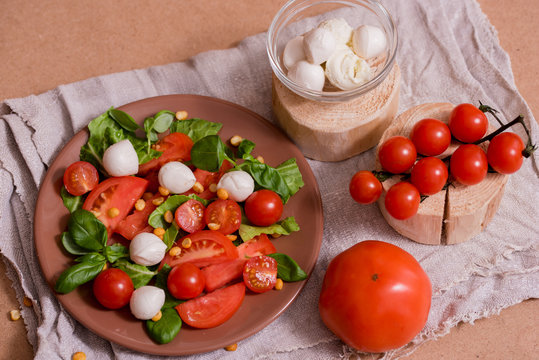 Traditional Italian fresh salad Caprese made of organic cherry tomatoes and mini mozzarella di Bufalla over a pheasant blue stone background. Healthy and traditional food concept. Top View. Copy space