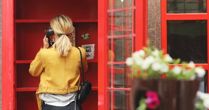 young handsome confident woman using call box with red background for calling making a call abroad cheapper communication business technology development royal modern lifestyle pay phone system