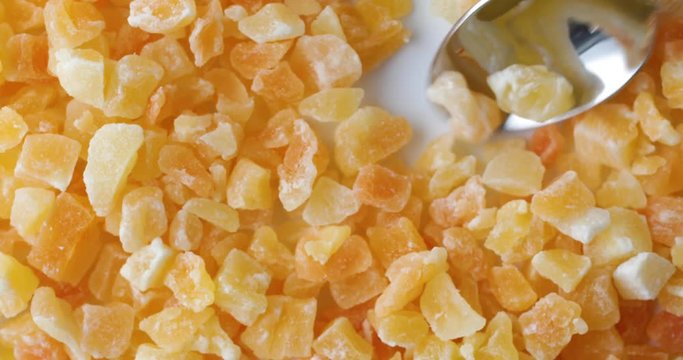 Close video of using a spoon to get a spoonful of dried diced cantaloupe on a plate.