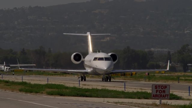 LUXURY JET TAXIING WITH TRAFFIC BEHIND, IN 4K.  Mild heat waves.