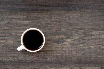 The cup of coffee on the wooden background