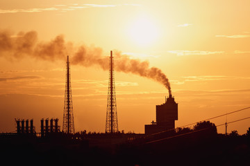 Silhouette power plant with cooling towers against sunset sky