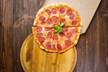 Pizza pepperoni with mozzarella cheese, salami and arugula in box on wooden background