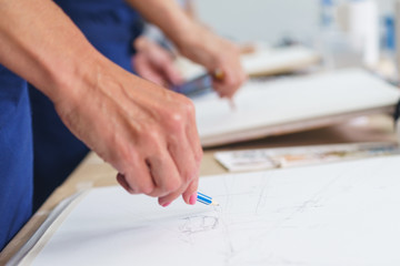 Artist sketches a pencil in a school of painting, preparing a blank canvas for the creation of a painting.