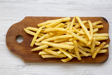 French fries on wooden board over white wooden background, top view. From above.