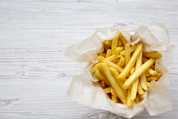 French fries over white wooden background, top view. Copy space.