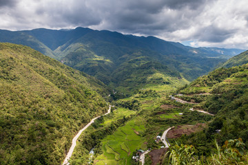 Fototapeta na wymiar Aerial drone view of huge rice terraces in a valley surrounded by tall mountains and low hanging cloud (Banaue)