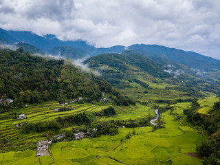 Aerial drone view of huge rice terraces in a valley surrounded by tall mountains and low hanging cloud (Banaue)