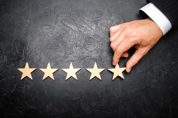 The businessman's hand in the suit holds the fifth star. Get the fifth star. The concept of the...