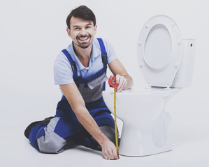 Plumber with tape measures distance from toilet to floor.