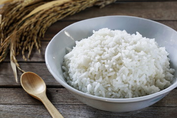 Jasmine rice in  bowl and paddy rice on a brown wooden background beautiful Thai food