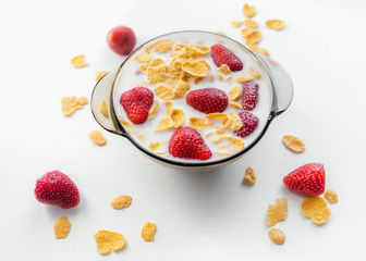 Bowl with strawberry and corn flakes in milk on white background